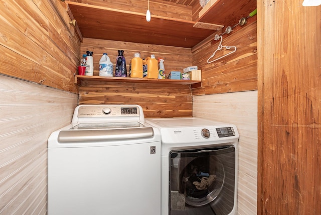 laundry room with laundry area, wood walls, and separate washer and dryer