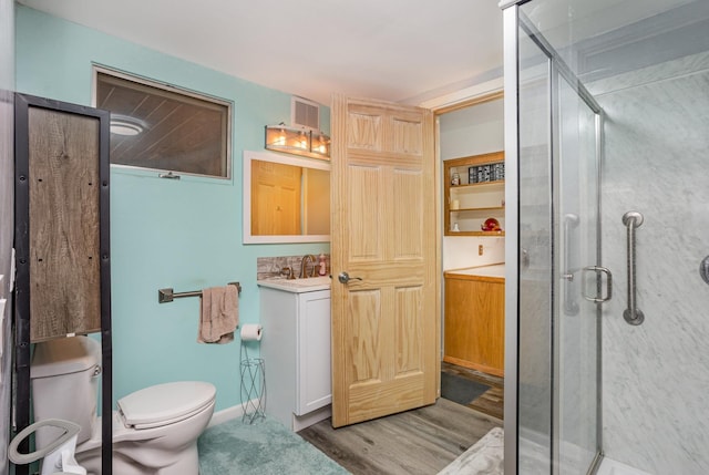 bathroom featuring a stall shower, visible vents, toilet, wood finished floors, and vanity