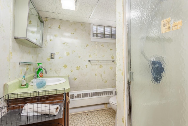 bathroom featuring a stall shower, a drop ceiling, toilet, radiator heating unit, and vanity