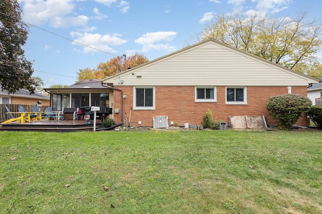 back of property with a yard, brick siding, cooling unit, and a sunroom