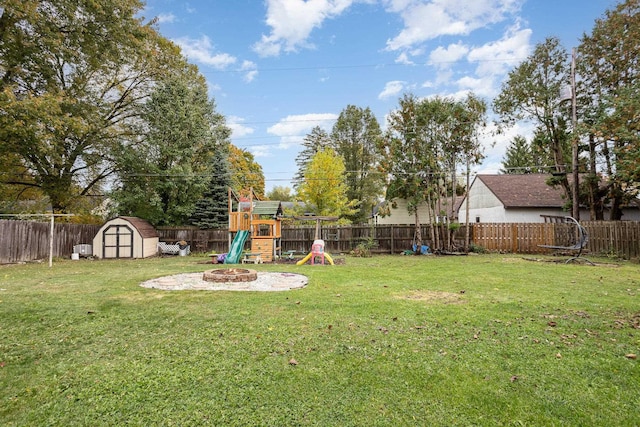 view of yard featuring a fire pit, a fenced backyard, an outbuilding, a shed, and a playground