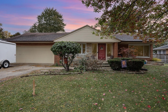 single story home with driveway, a garage, a lawn, and brick siding