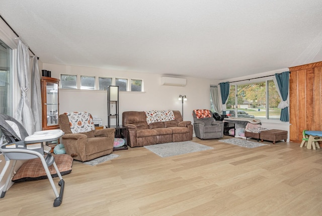 living area featuring a textured ceiling, a wall mounted AC, and wood finished floors