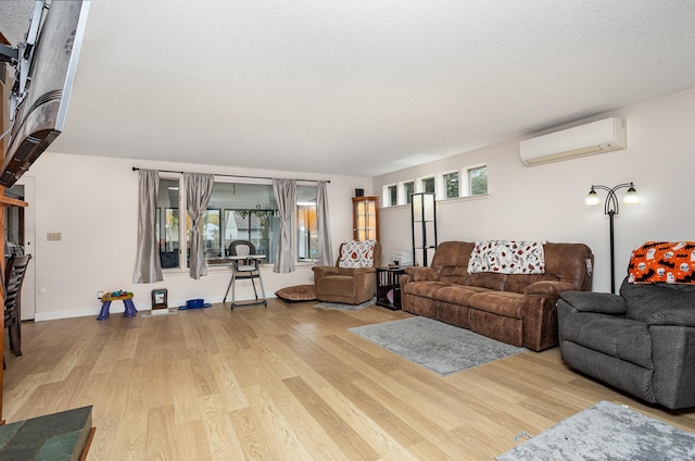 living room featuring an AC wall unit, a textured ceiling, and wood finished floors