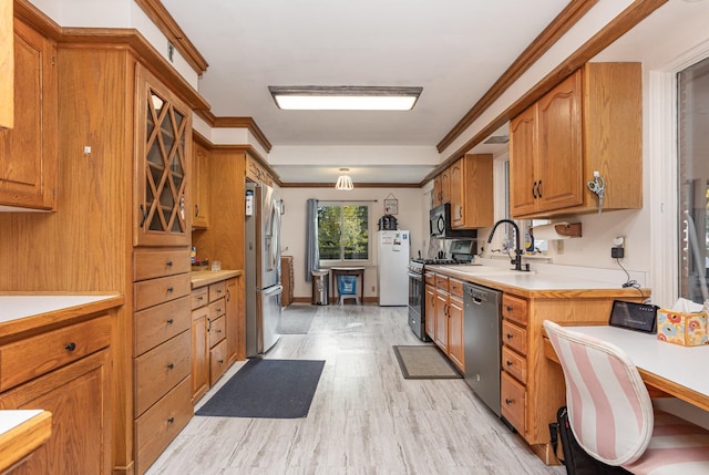 kitchen featuring appliances with stainless steel finishes, brown cabinets, ornamental molding, light countertops, and a sink