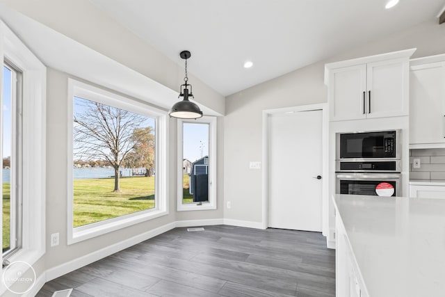 kitchen featuring black microwave, plenty of natural light, lofted ceiling, and stainless steel oven