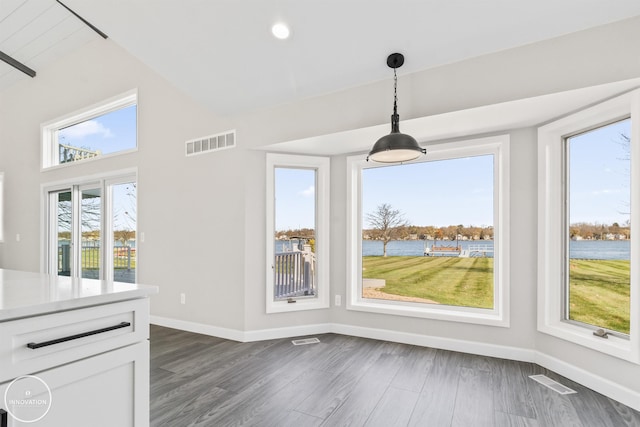 unfurnished dining area featuring dark wood-type flooring, visible vents, and baseboards