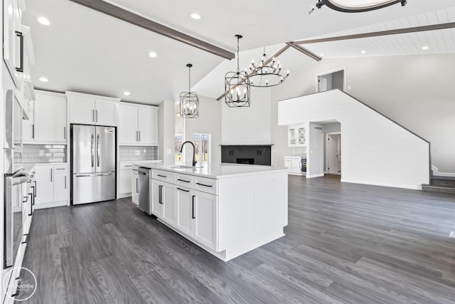 kitchen featuring a sink, open floor plan, appliances with stainless steel finishes, backsplash, and beam ceiling