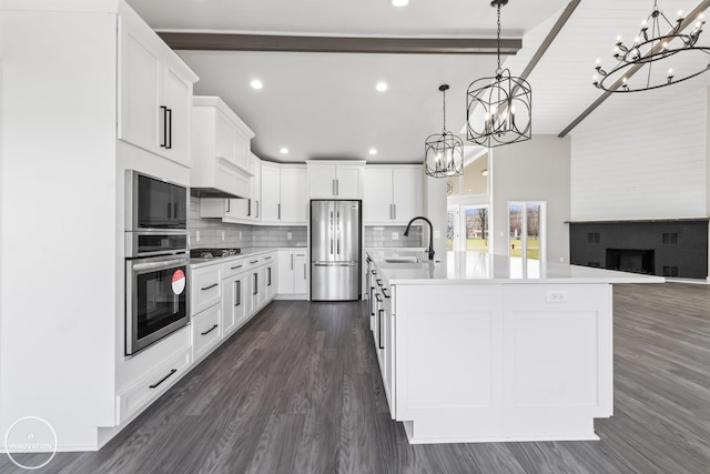 kitchen with white cabinets, a sink, stainless steel appliances, light countertops, and backsplash