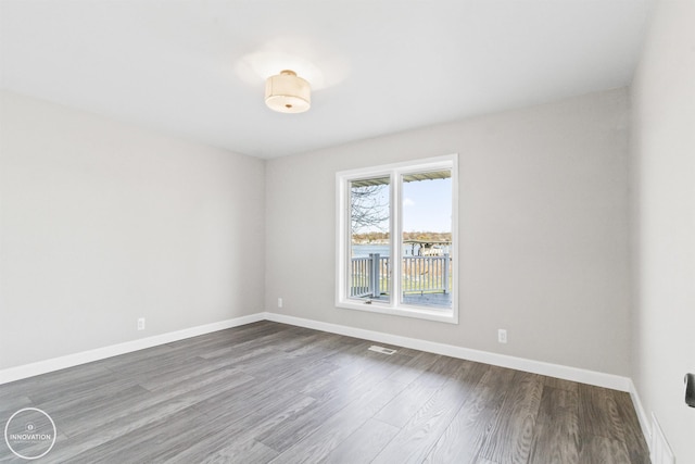 spare room featuring dark wood-style floors, visible vents, and baseboards