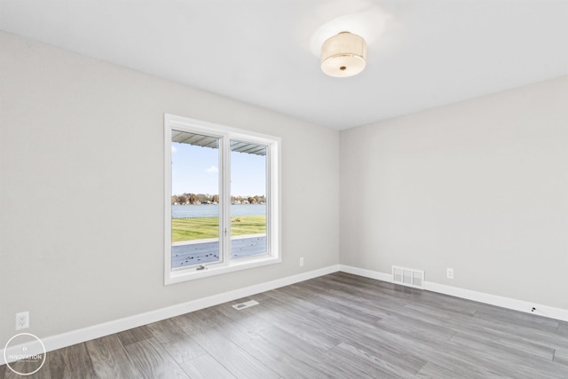 spare room featuring visible vents, baseboards, and wood finished floors