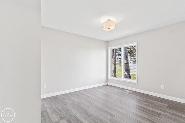 unfurnished room with visible vents, baseboards, and wood finished floors