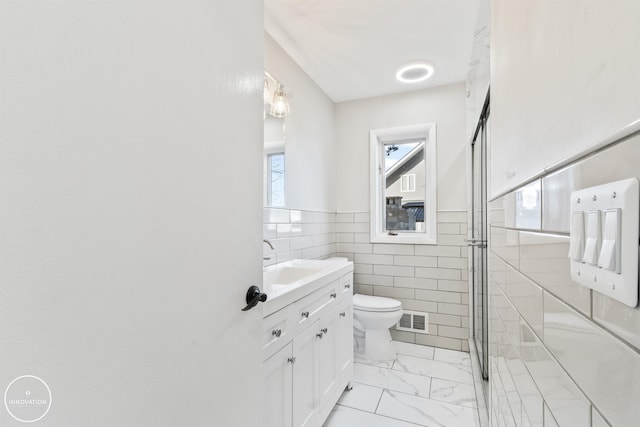 bathroom featuring toilet, vanity, visible vents, tile walls, and marble finish floor