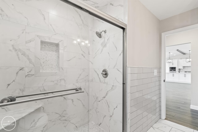 full bath featuring marble finish floor, a marble finish shower, and tile walls