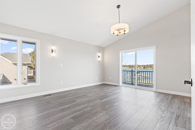 unfurnished room featuring visible vents, baseboards, vaulted ceiling, and wood finished floors