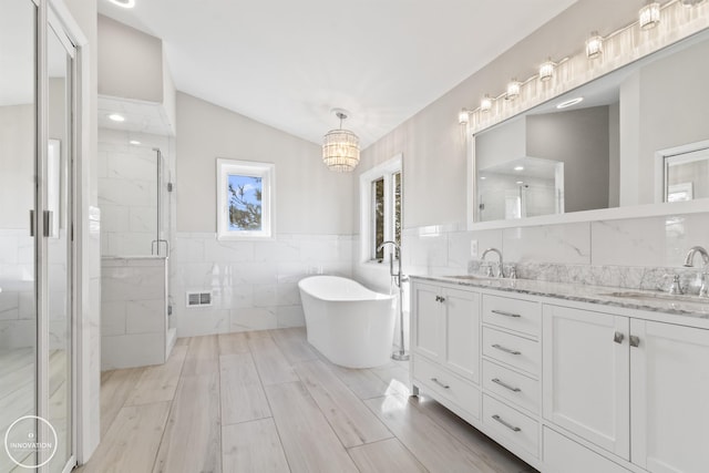 bathroom featuring double vanity, a sink, a marble finish shower, and tile walls