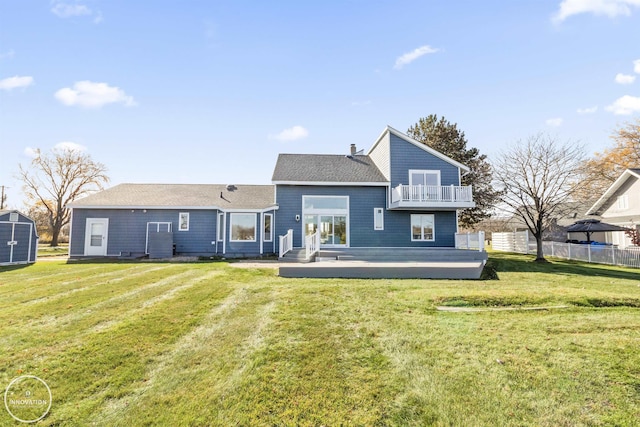 back of house featuring a balcony, a wooden deck, fence, and a yard