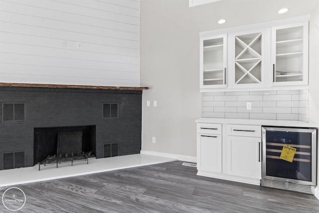 bar featuring beverage cooler, a fireplace, visible vents, a bar, and dark wood finished floors