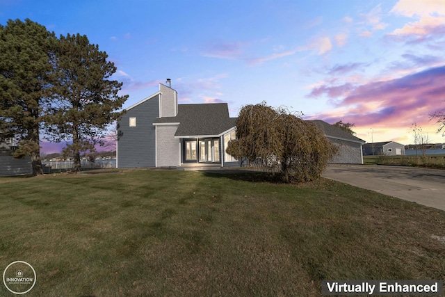 view of front of home featuring driveway, a lawn, and a chimney