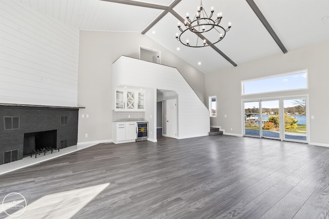 unfurnished living room with visible vents, dark wood finished floors, wine cooler, stairway, and a fireplace