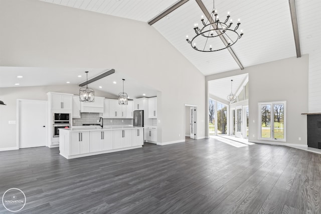 unfurnished living room featuring baseboards, a chandelier, dark wood-style flooring, and beam ceiling