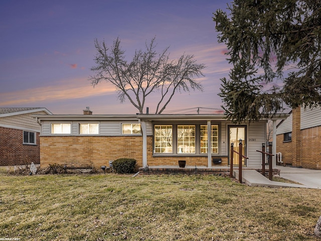 ranch-style house featuring brick siding and a lawn