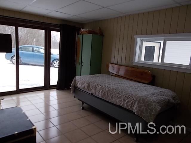 bedroom featuring wood walls, a paneled ceiling, and access to exterior