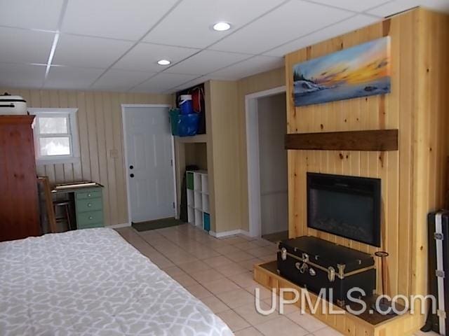 tiled bedroom with a paneled ceiling, a closet, and a glass covered fireplace