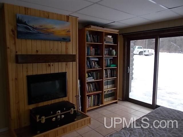 interior space featuring wood walls, a drop ceiling, and tile patterned flooring