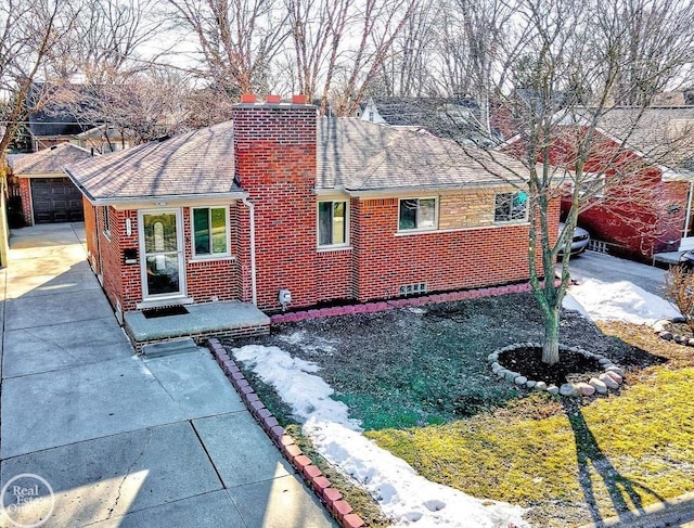 view of front facade featuring brick siding, an outdoor structure, and a chimney