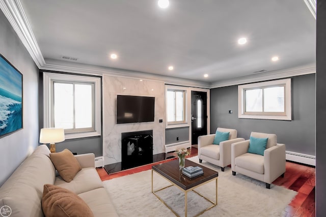 living area with a baseboard heating unit, a high end fireplace, light wood-style flooring, and crown molding