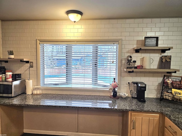 kitchen with tasteful backsplash, stainless steel microwave, dark stone countertops, and open shelves