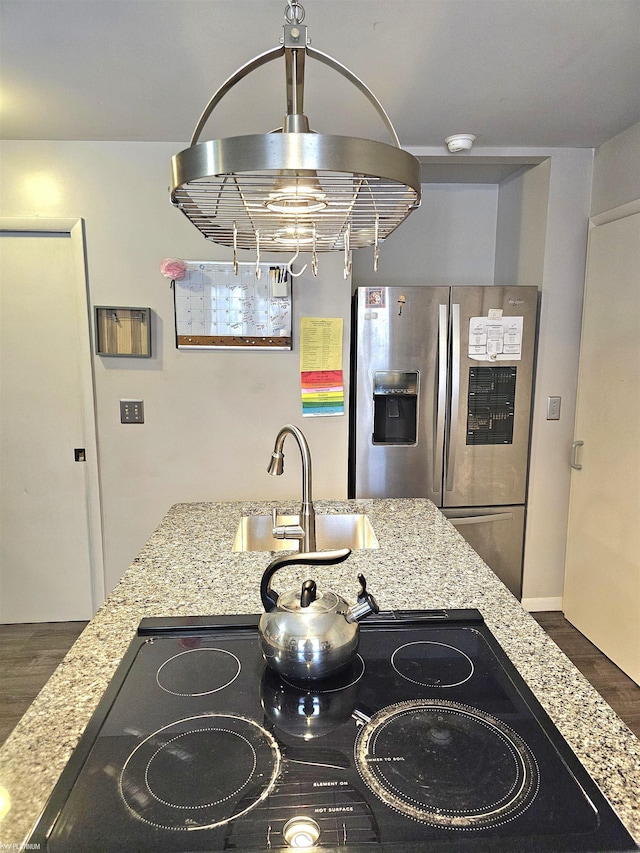 kitchen with dark wood-style floors, a sink, stainless steel fridge with ice dispenser, and light stone countertops