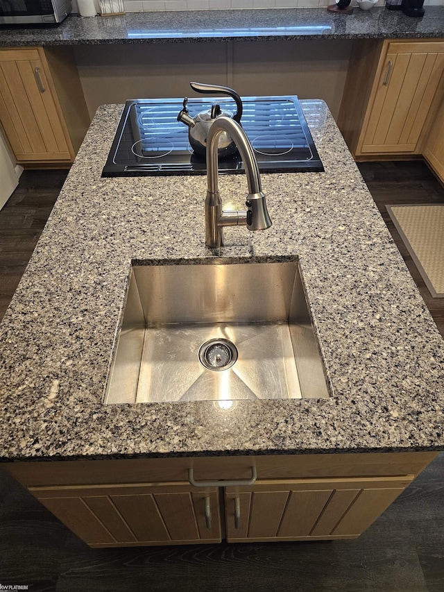 room details featuring dark wood-type flooring, black stovetop, and a sink