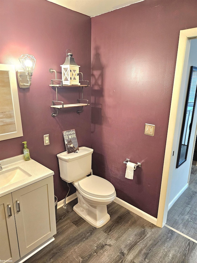 bathroom with baseboards, vanity, toilet, and wood finished floors