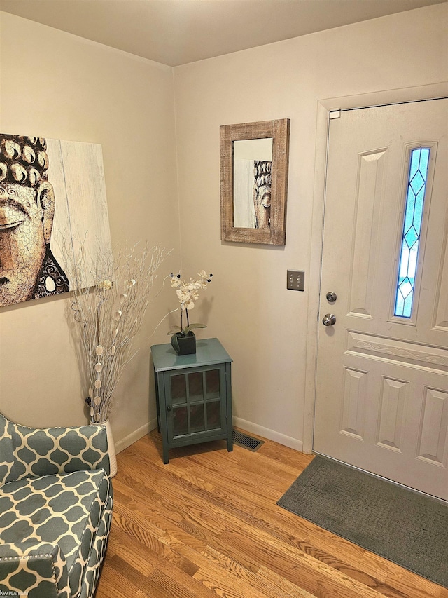 foyer featuring visible vents, baseboards, and wood finished floors