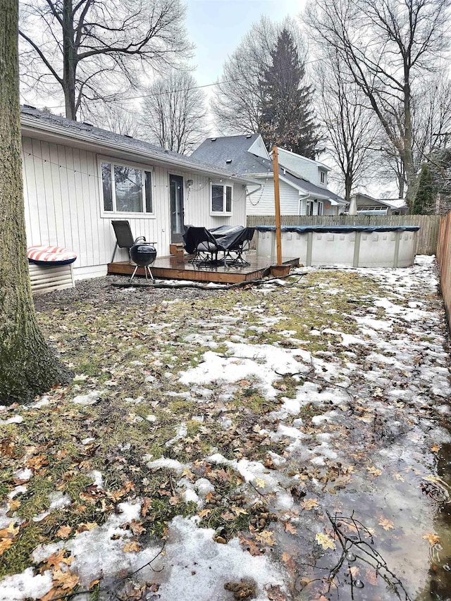 back of property with a covered pool, fence, and a wooden deck