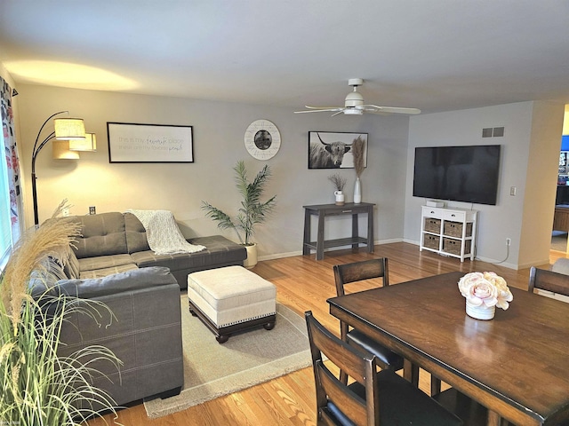 living room featuring ceiling fan, wood finished floors, visible vents, and baseboards