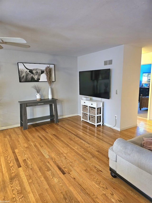 living room with wood finished floors, visible vents, and baseboards