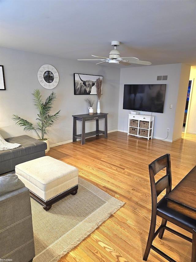 living area featuring ceiling fan, wood finished floors, visible vents, and baseboards