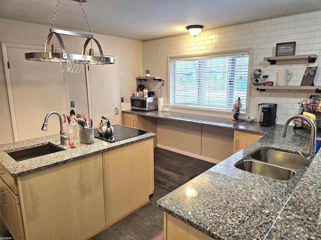 kitchen featuring stainless steel microwave, a sink, a kitchen island with sink, and backsplash