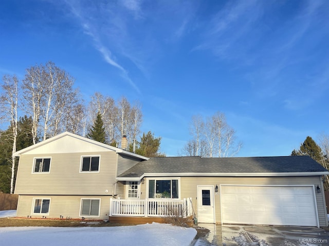 split level home featuring an attached garage, driveway, a chimney, and roof with shingles