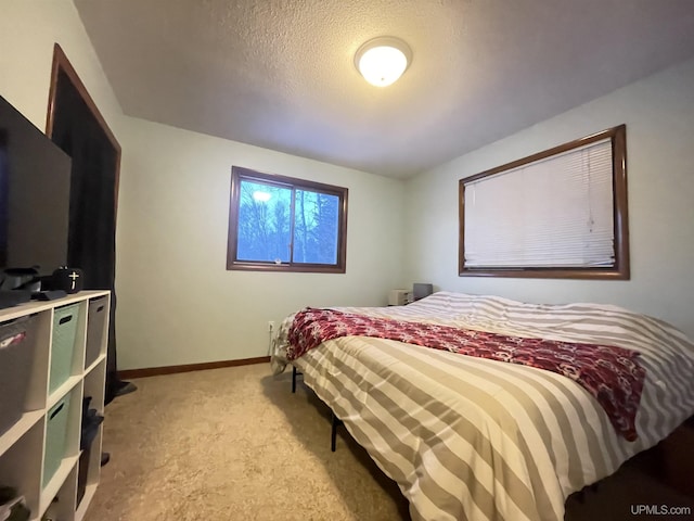 bedroom featuring light carpet, a textured ceiling, and baseboards