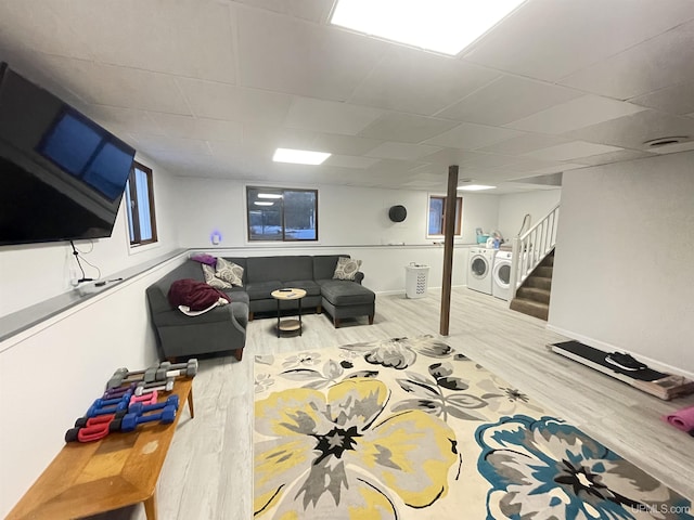 living area featuring a drop ceiling, wood finished floors, baseboards, stairway, and washing machine and clothes dryer