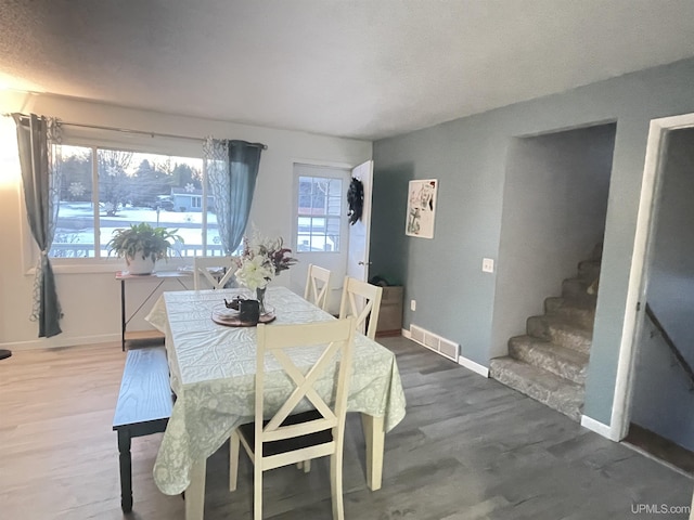 dining area featuring stairway, wood finished floors, visible vents, and baseboards