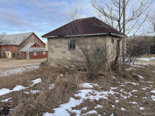 view of snow covered exterior with concrete block siding and an outdoor structure