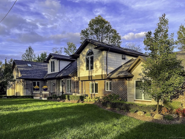 back of property with brick siding, a lawn, and roof with shingles