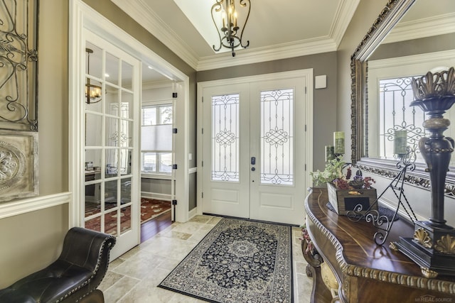 foyer entrance featuring a chandelier, french doors, and crown molding