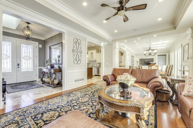 living area with a wainscoted wall, crown molding, visible vents, a decorative wall, and wood finished floors