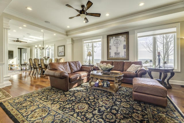 living area featuring decorative columns, ornamental molding, wood finished floors, ceiling fan with notable chandelier, and recessed lighting